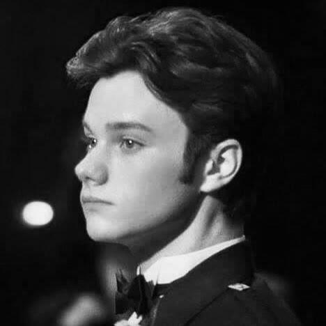 a black and white photo of kurt hummel from glee looking right.