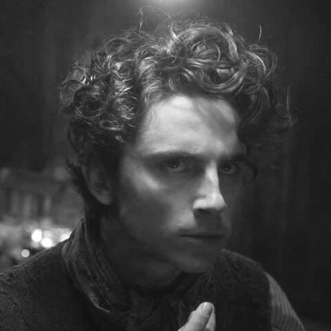 a black and white photo of willy wonka from wonka (2023) looking right.